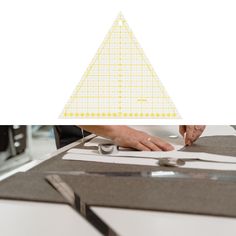 a person cutting paper on top of a table next to a ruler and tape measure