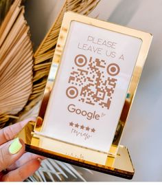 a person holding up a gold frame with a qr code on it and the words please leave us a google