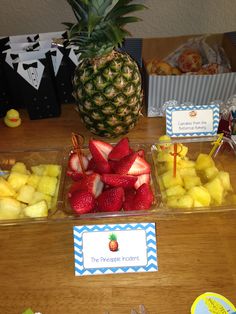 there is a pineapple and strawberries on the table with place cards for guests