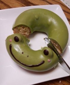 a green donut with a smiley face on it and a knife in the middle