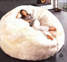 a woman laying on top of a large white bean bag chair in a living room