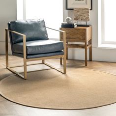 a living room with a chair, table and rug on the floor in front of a window