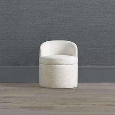 a white chair sitting on top of a hard wood floor next to a gray wall