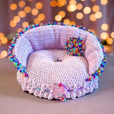 a crocheted basket with pom poms on the inside and bottom, sitting on a table