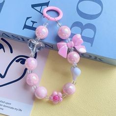 a pink and white beaded bracelet on top of a blue book next to a pair of scissors