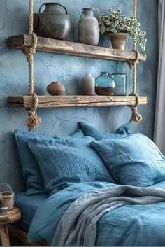 a bed with blue sheets and pillows in front of a wall mounted shelf filled with vases