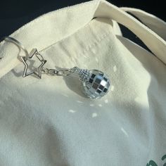 a white bag with a silver charm hanging from it's side