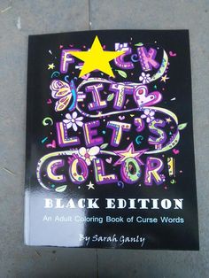 a book that is laying on the ground with words written in different colors and shapes