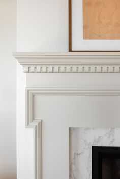 a white fireplace with a painting on the mantle