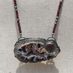 a necklace that has been made with silver and red beads on the end of it