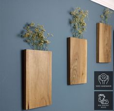 three wooden vases with flowers in them on a wall next to a blue wall