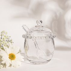 there is a glass jar with spoons in it next to a white flower on the table