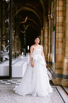 a woman standing in front of a building wearing a white dress