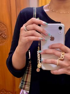 a woman is holding up her cell phone in front of her face and wearing gold rings