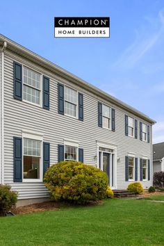 a white house with blue shutters and green grass in front of it that says champion home builder