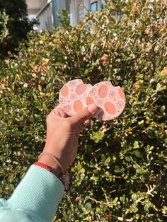 a person holding up two pieces of paper in front of bushes