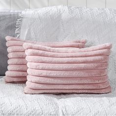 a stack of pink towels sitting on top of a white couch