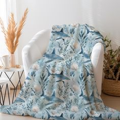 a blue and white blanket sitting on top of a chair next to a potted plant