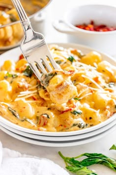 a fork is being lifted from a plate of ravioli with cheese and spinach