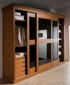 a large wooden cabinet with glass doors on the front and bottom, in a room with hard wood flooring