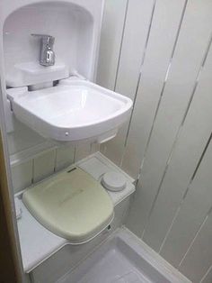 a white toilet sitting next to a sink in a bathroom under a faucet