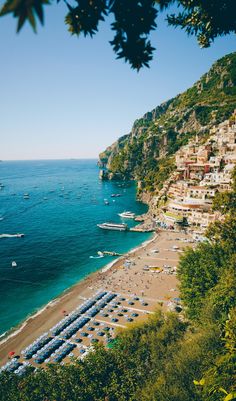 the beach is lined with umbrellas and parked boats on it's shore line