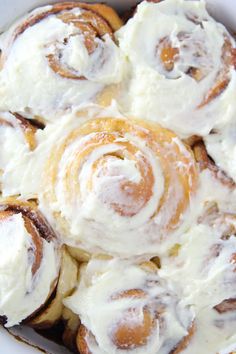 cinnamon rolls with cream cheese frosting in a white bowl on a yellow and black background