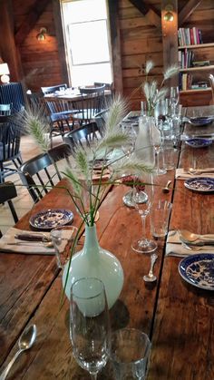 a wooden table topped with plates and vases filled with flowers on top of it