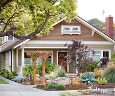 a house with landscaping in front of it and trees on the other side of the house