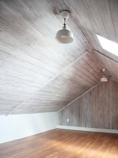 an empty room with wood flooring and skylights in the ceiling is seen here