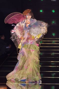 a woman is walking down the runway in a dress with large wings on it's back