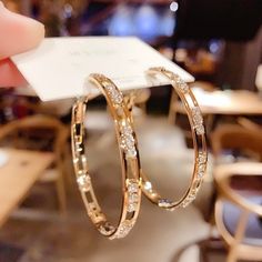 a pair of gold hoop earrings on display in a store or restaurant, with a price tag attached to it