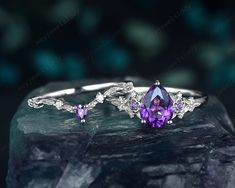 an amethoraite and diamond ring sitting on top of a rock with crystal stones