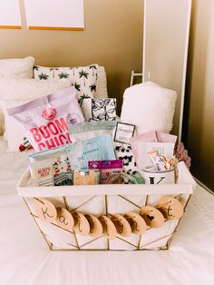 a basket filled with lots of items on top of a white bed covered in pillows