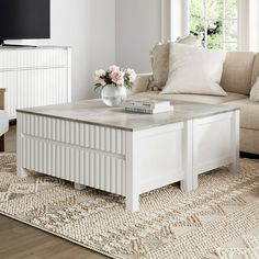 a living room with a couch, coffee table and television on top of the tv stand