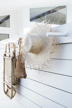 a hat hanging on the side of a white wall next to purses and towels