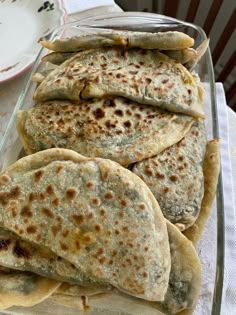 several pita breads in a glass dish on a table