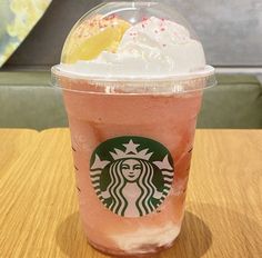 a starbucks drink with whipped cream and sprinkles on the top sits on a table