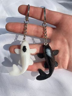 two black and white fish keychains are being held in someone's hand