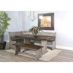 a dining room table with benches and a potted plant in the corner next to it