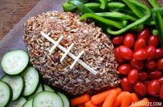 a football ball surrounded by vegetables and cucumbers on a cutting board with carrots