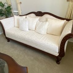 a white couch sitting in a living room next to a window