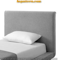 a bed with white pillows and a gray headboard