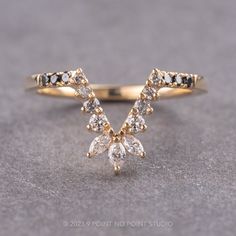 a yellow gold ring with three pear shaped diamonds on it's side, sitting on a gray surface