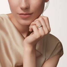 a woman in a beige dress with a ring on her finger