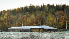 a house in the middle of a field surrounded by trees and grass with frost on it