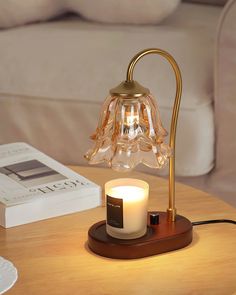 a table with a lit candle on it and a book in front of the lamp