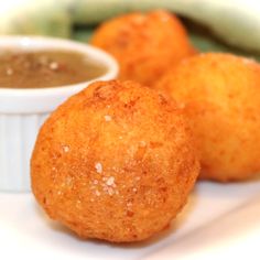 three fried food items on a white plate with dipping sauce in the bowl next to them