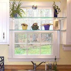 a kitchen sink sitting under a window next to a counter top with pots and pans on it