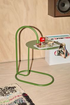 a small table with a green metal stand on top of it next to a speaker